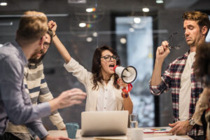 Bossy female leader encouraging her coworkers to work harder in the office.